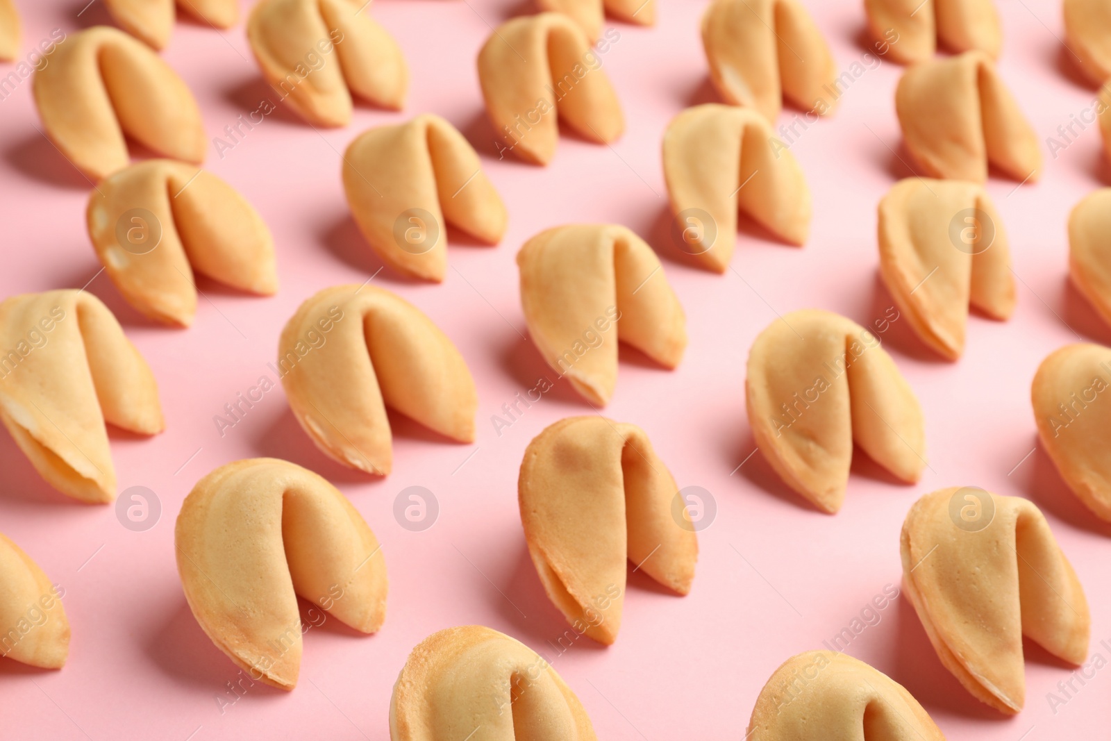 Photo of Many tasty fortune cookies with predictions on pink background