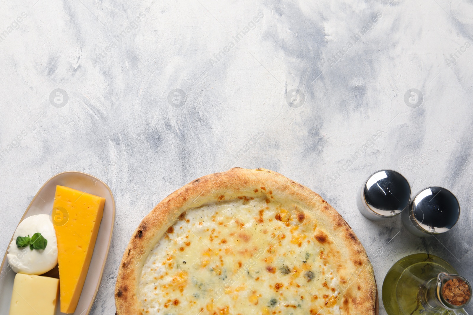 Photo of Delicious cheese pizza, oil and different kinds of cheese on light grey textured table, flat lay. Space for text