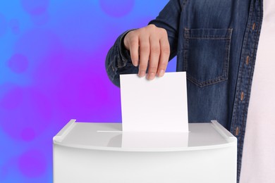 Woman putting her vote into ballot box on color background, closeup