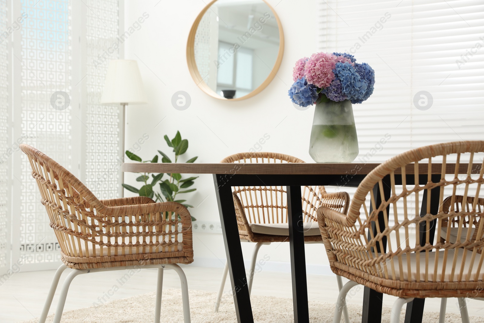 Photo of Vase with hydrangea flowers on wooden table in stylish dining room