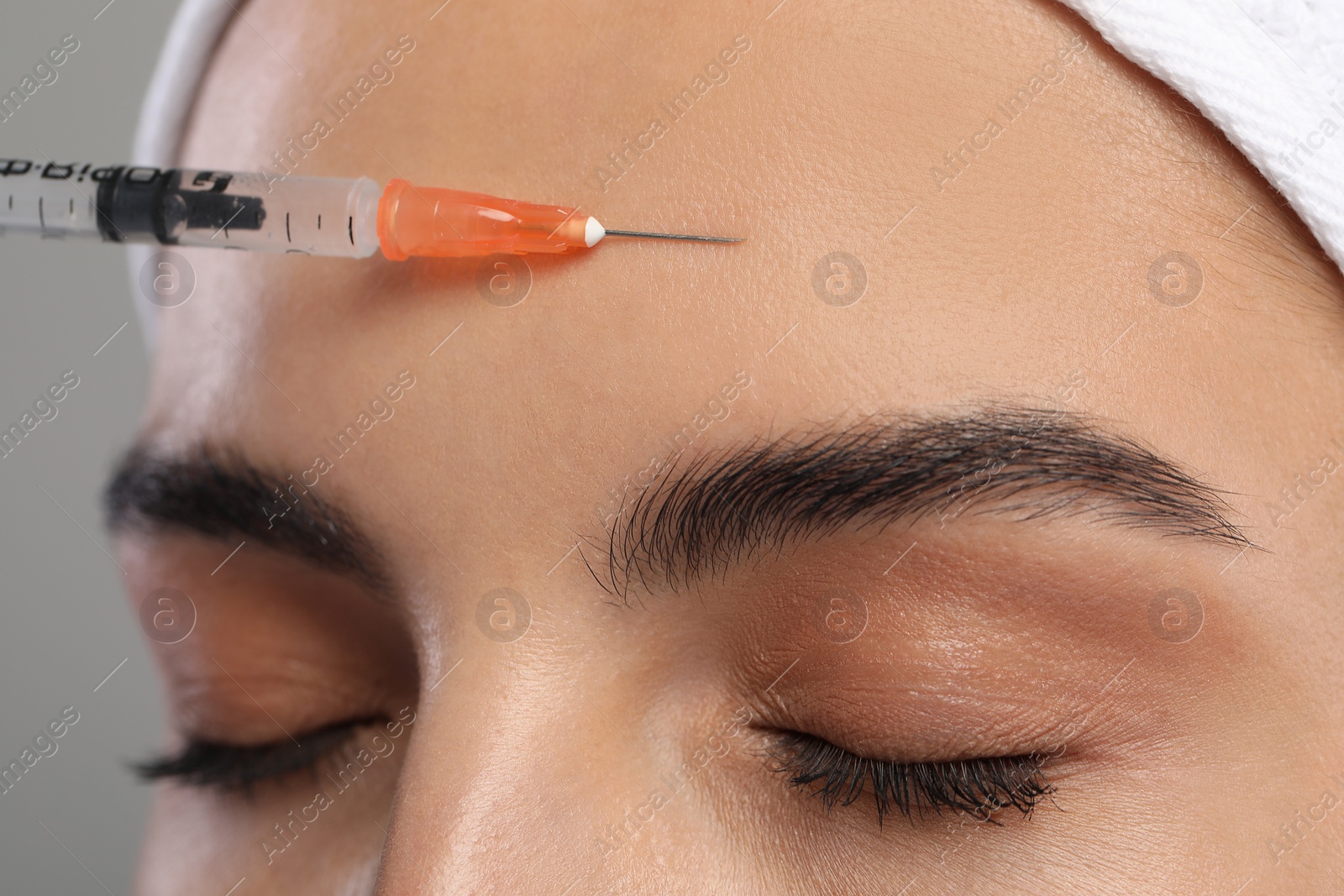 Photo of Young woman getting facial injection on light grey background, closeup. Cosmetic surgery