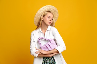 Beautiful stylish woman with trendy baguette bag on yellow background