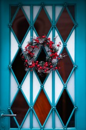 Beautiful Christmas wreath with berries and cones hanging on door