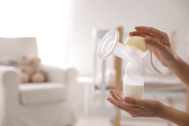 Closeup view of woman holding manual breast pump indoors, space for text. Baby health