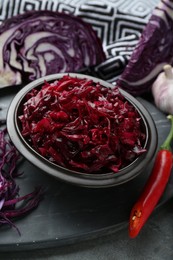 Tasty red cabbage sauerkraut and ingredients on grey table