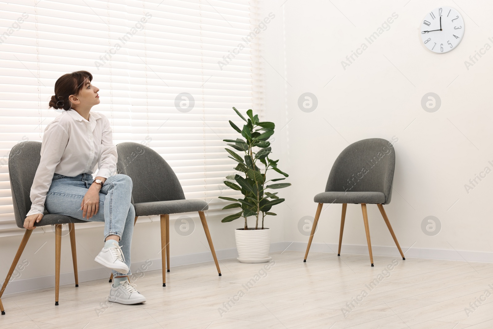 Photo of Woman sitting on chair and waiting for appointment indoors