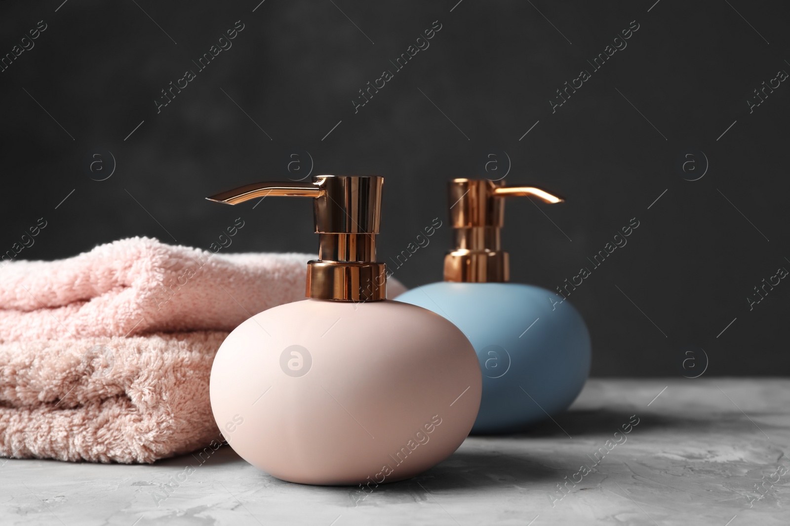 Photo of New stylish soap dispensers and towels on table