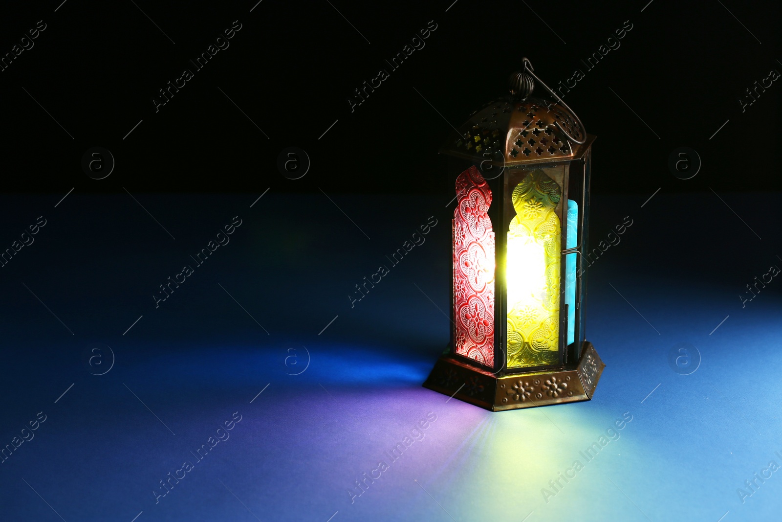 Photo of Decorative Arabic lantern on table against dark background. Space for text