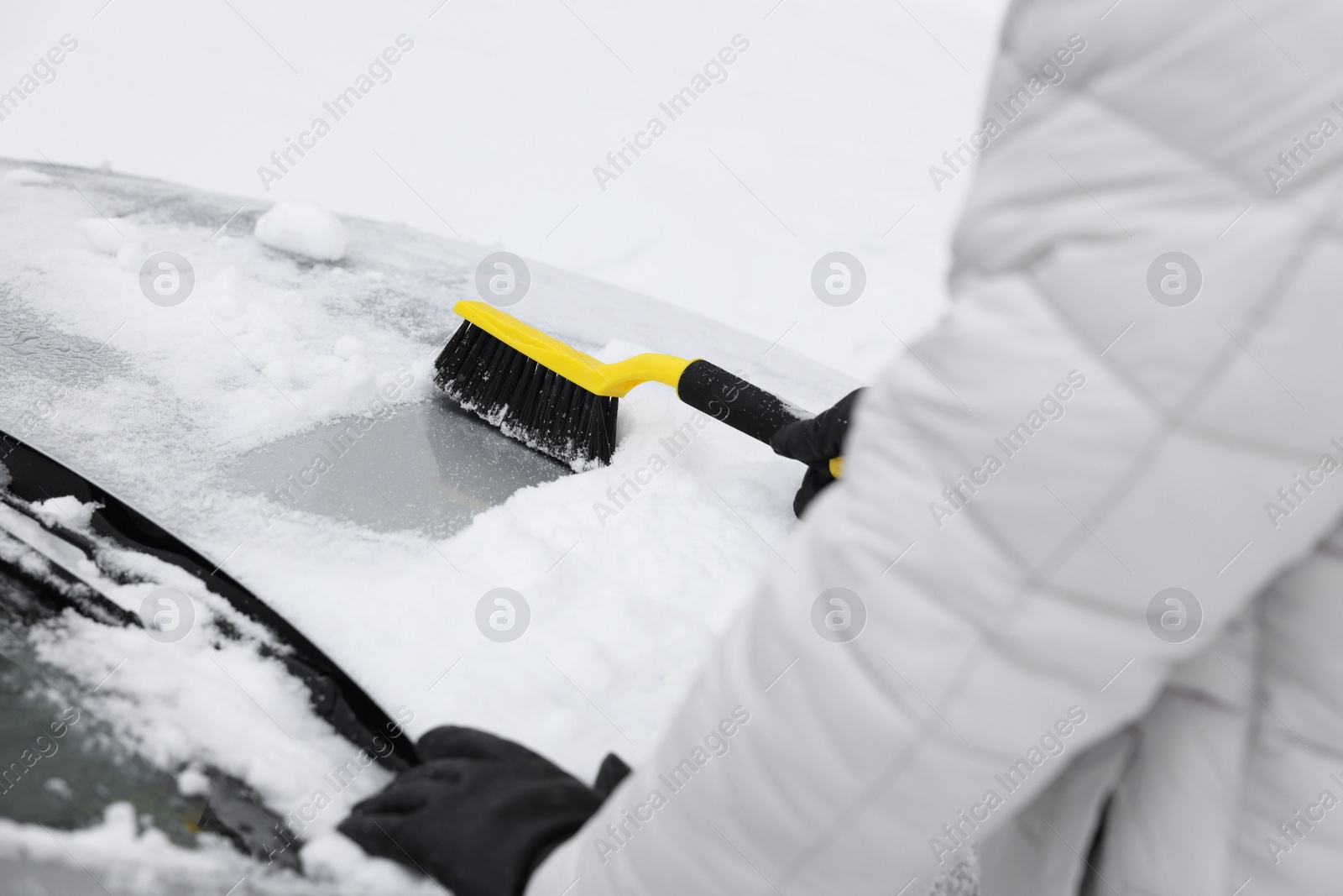 Photo of Man cleaning snow from car hood outdoors, closeup