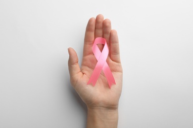 Photo of Woman holding pink ribbon on white background, top view. Breast cancer awareness concept