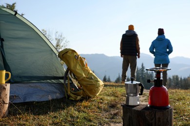 Photo of Couple enjoying beautiful mountain landscape in camping, focus on burner and moka pot