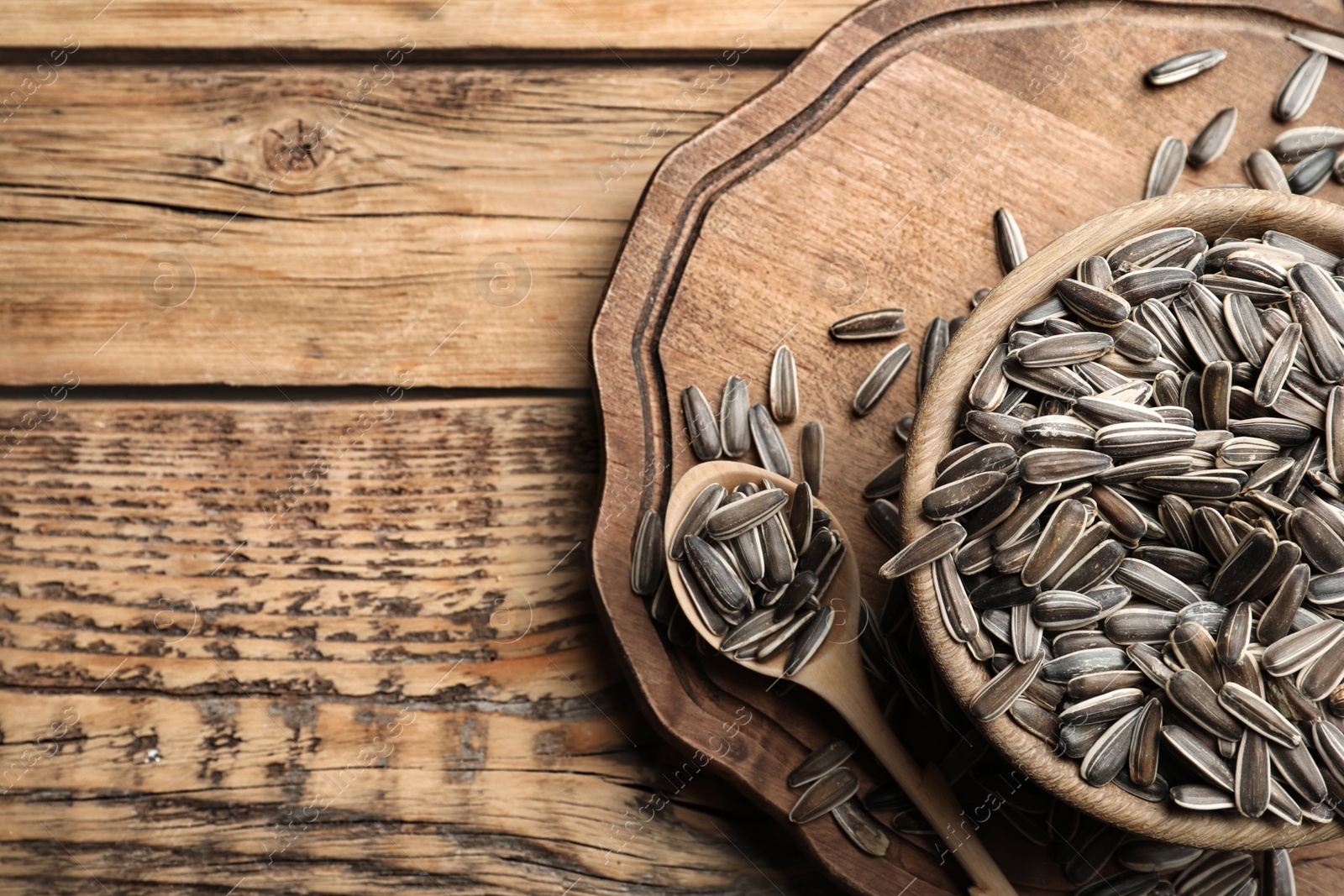 Photo of Raw sunflower seeds on wooden table, flat lay. Space for text