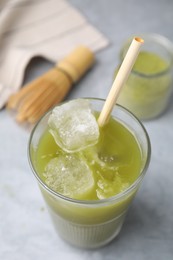 Glass of delicious iced green matcha tea on light grey table, above view