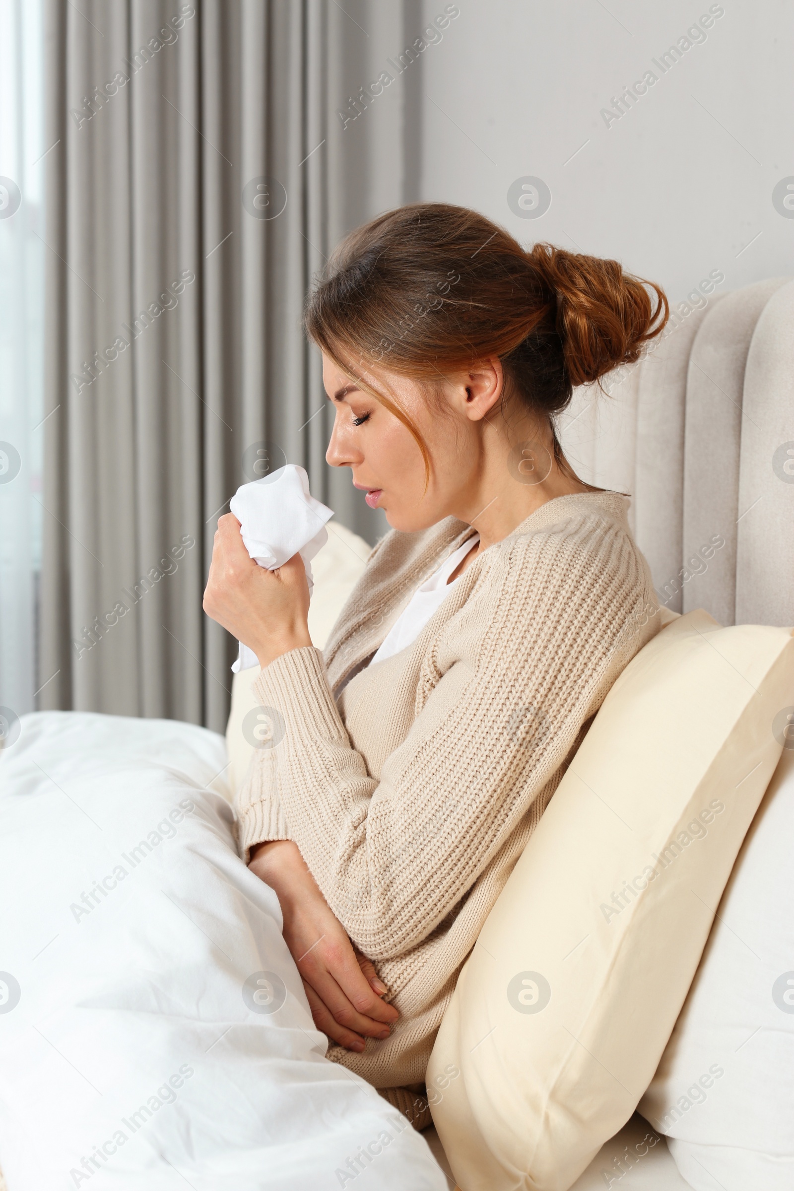 Photo of Sick woman with tissue coughing in bed at home