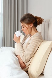 Sick woman with tissue coughing in bed at home