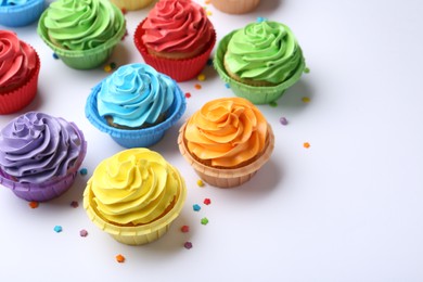 Photo of Many tasty cupcakes with bright cream and sprinkles on white background. Space for text