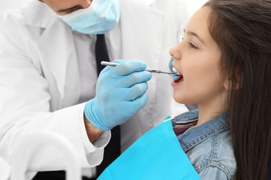 Photo of Professional dentist working with little girl in clinic