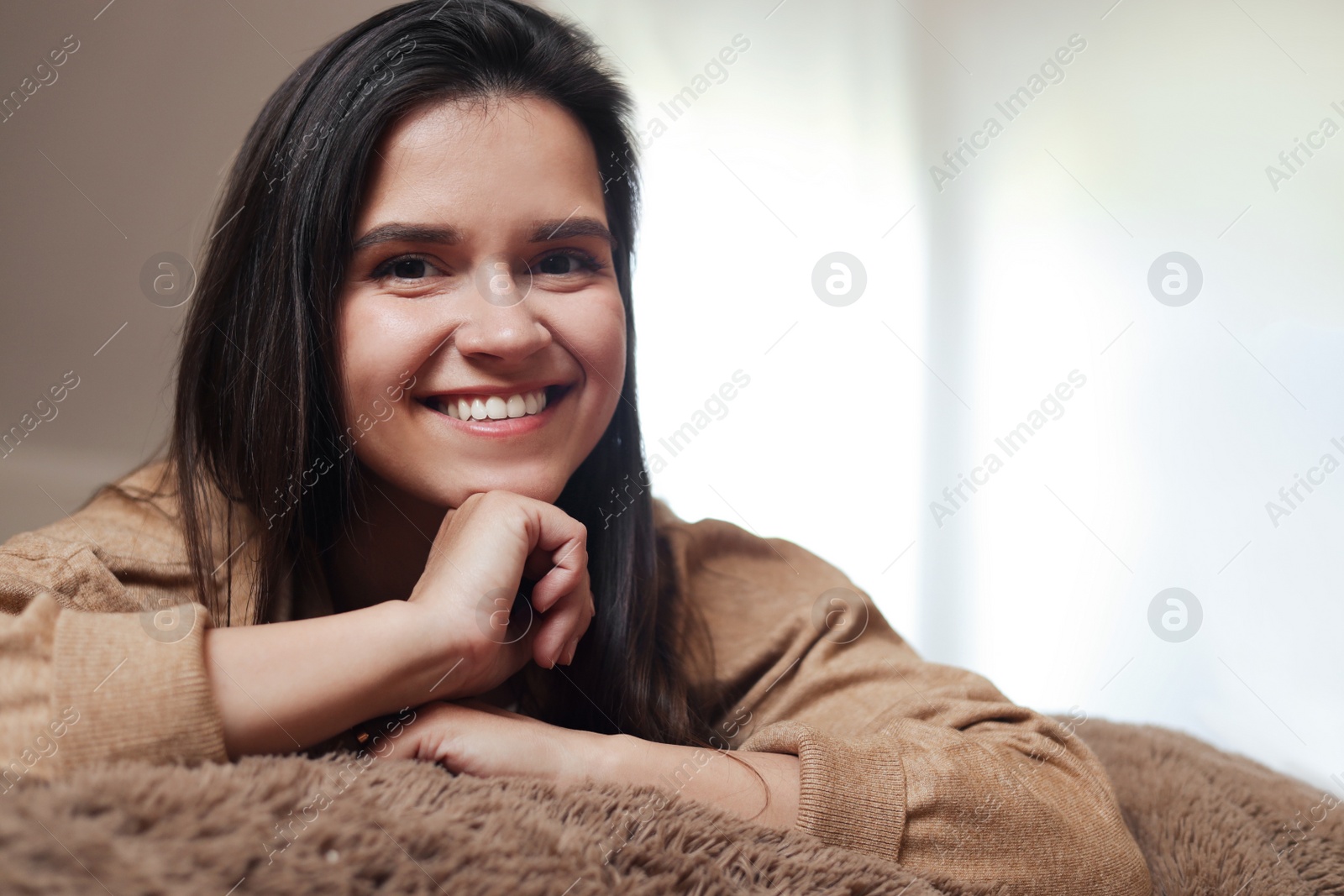 Photo of Portrait of beautiful young woman lying on bed at home, space for text