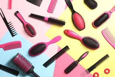 Different hair brushes, combs and scrunchies on color background, flat lay