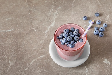 Photo of Glass with blueberry smoothie on grey background. Space for text