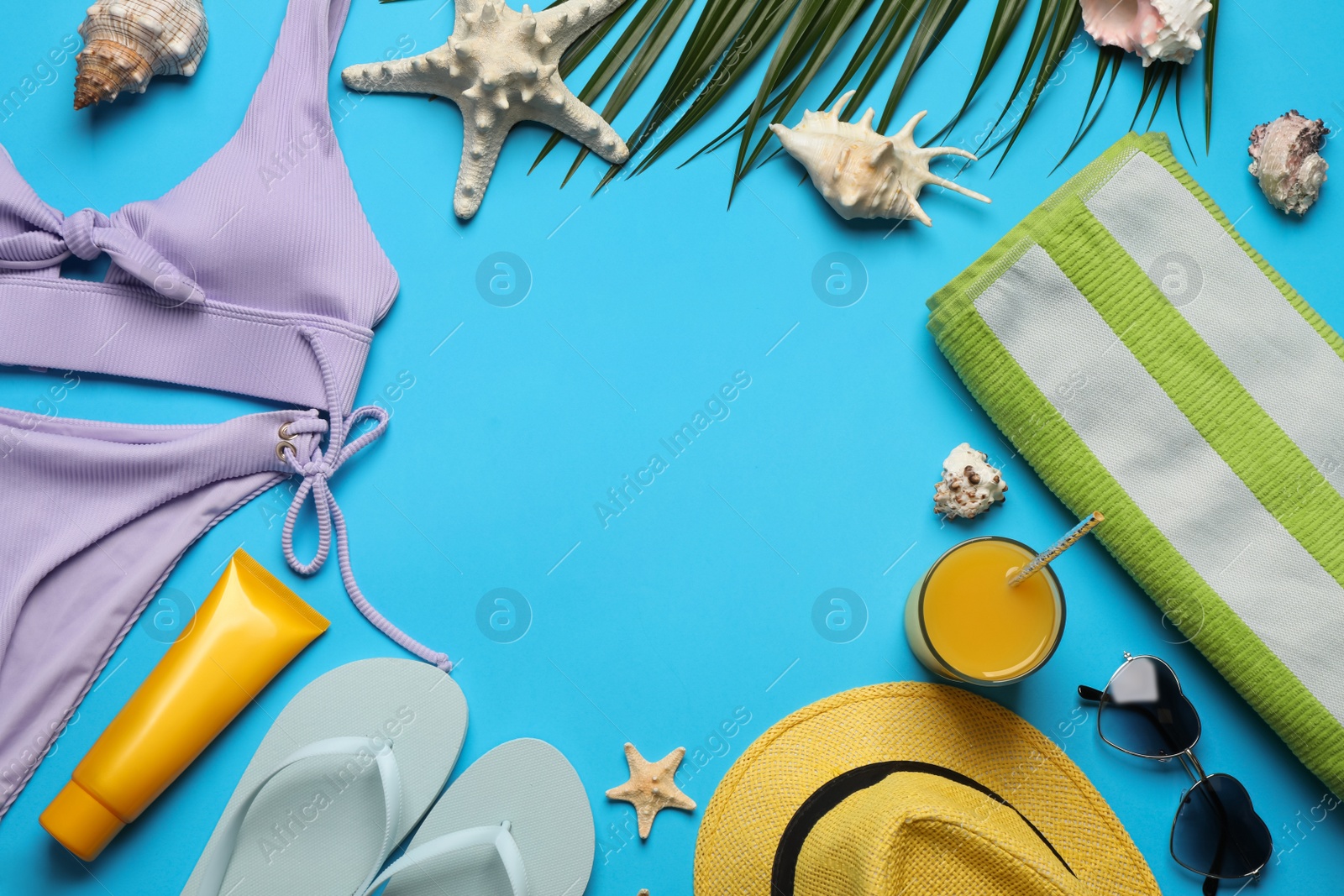 Photo of Frame of different beach objects on light blue background, flat lay. Space for text