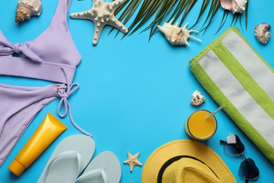 Frame of different beach objects on light blue background, flat lay. Space for text