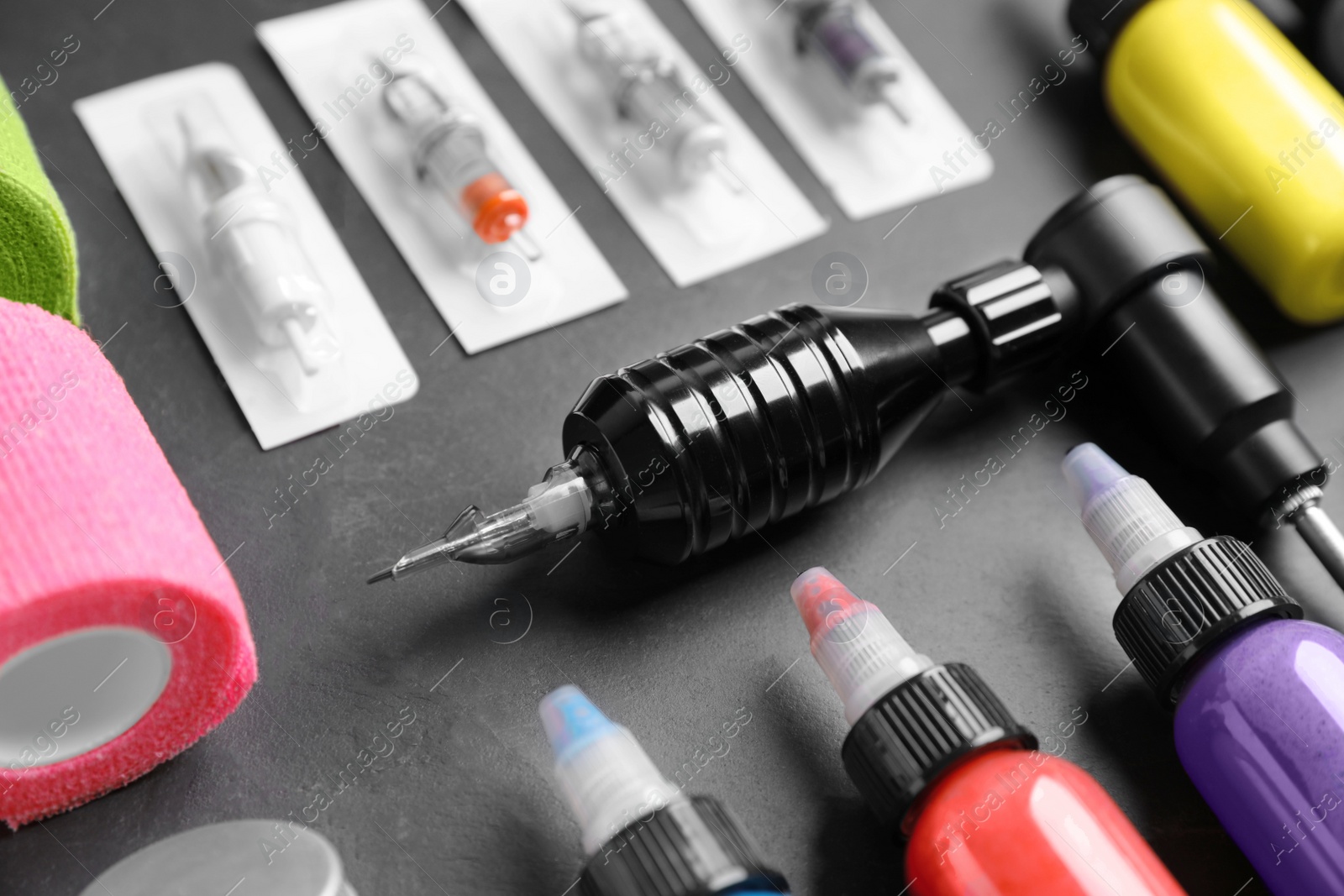 Photo of Tattoo machine and inks on black table, closeup