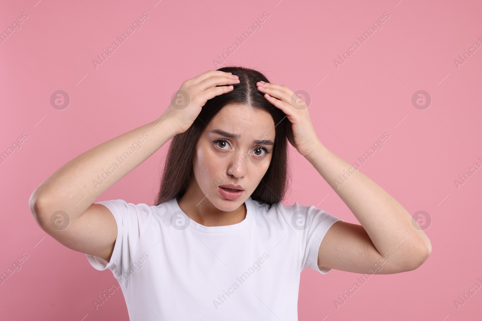 Photo of Sad woman examining her hair and scalp on pink background. Dandruff problem