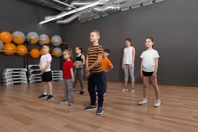 Photo of Cute little children and trainer doing physical exercise in school gym. Healthy lifestyle