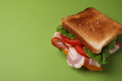 Photo of Tasty sandwich with bacon and tomato on green table, space for text