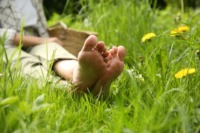 Photo of Woman sitting barefoot on green grass outdoors, closeup