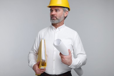 Photo of Architect in hard hat holding folder and draft on grey background