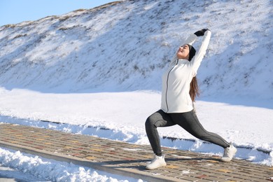 Photo of Woman doing sports exercises outdoors on winter day. Space for text