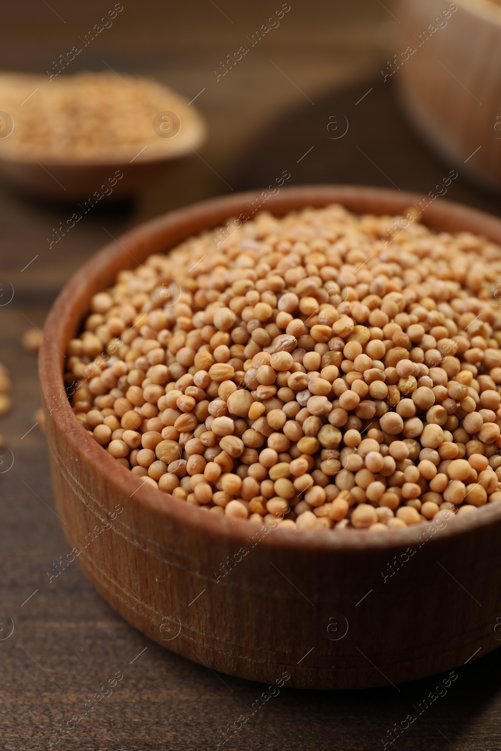 Photo of Mustard seeds in wooden bowl on table, closeup