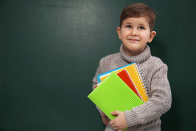 Photo of Cute little child near chalkboard, space for text. First time at school