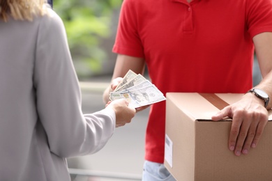 Photo of Woman paying courier for delivered parcel on doorstep