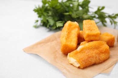 Photo of Tasty fried mozzarella sticks on white table, closeup. Space for text