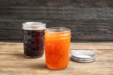 Two jars with tasty sweet jam on wooden table
