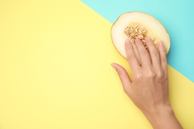 Photo of Young woman touching half of melon on color background, flat lay with space for text. Sex concept