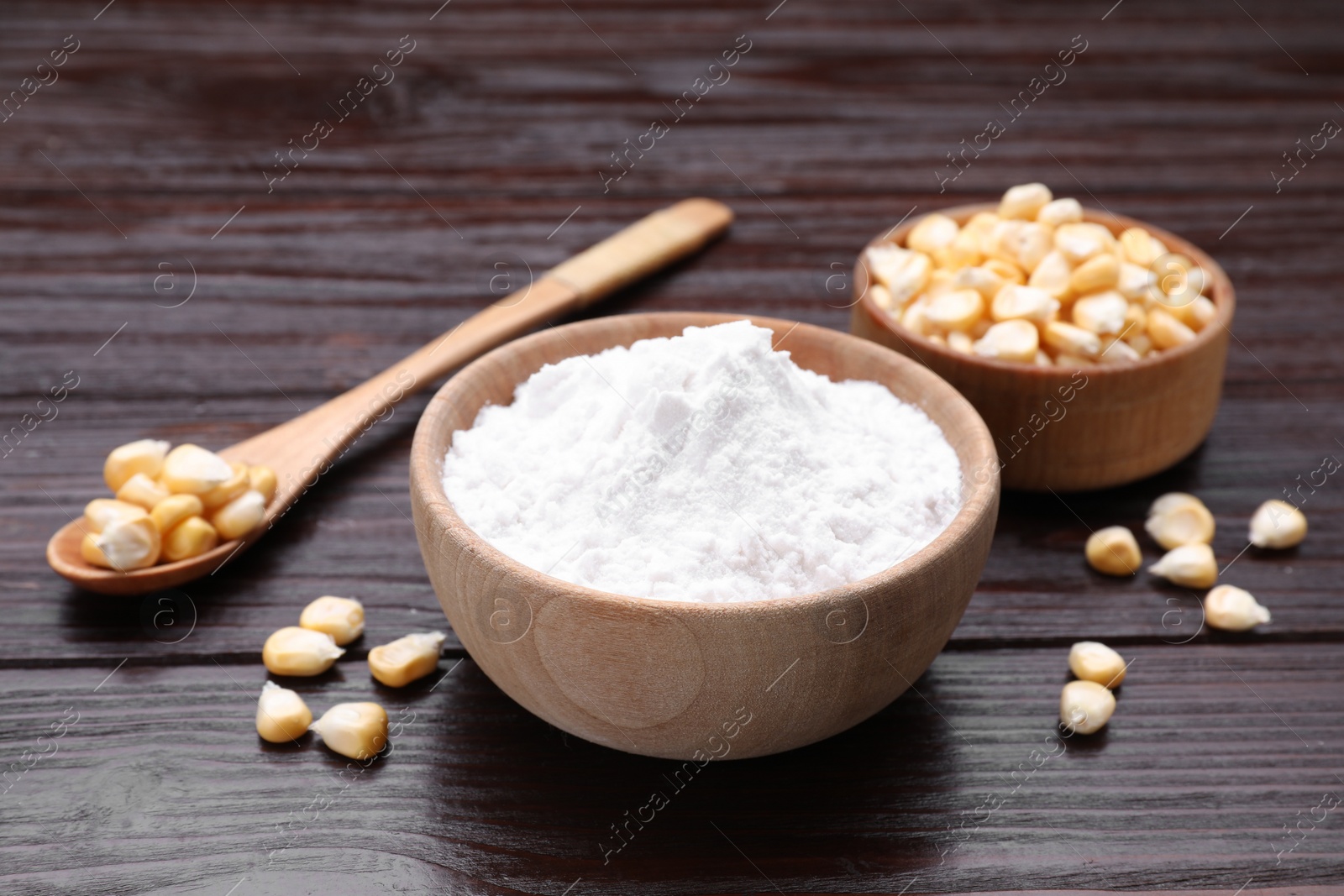 Photo of Bowl of corn starch and kernels on dark wooden table