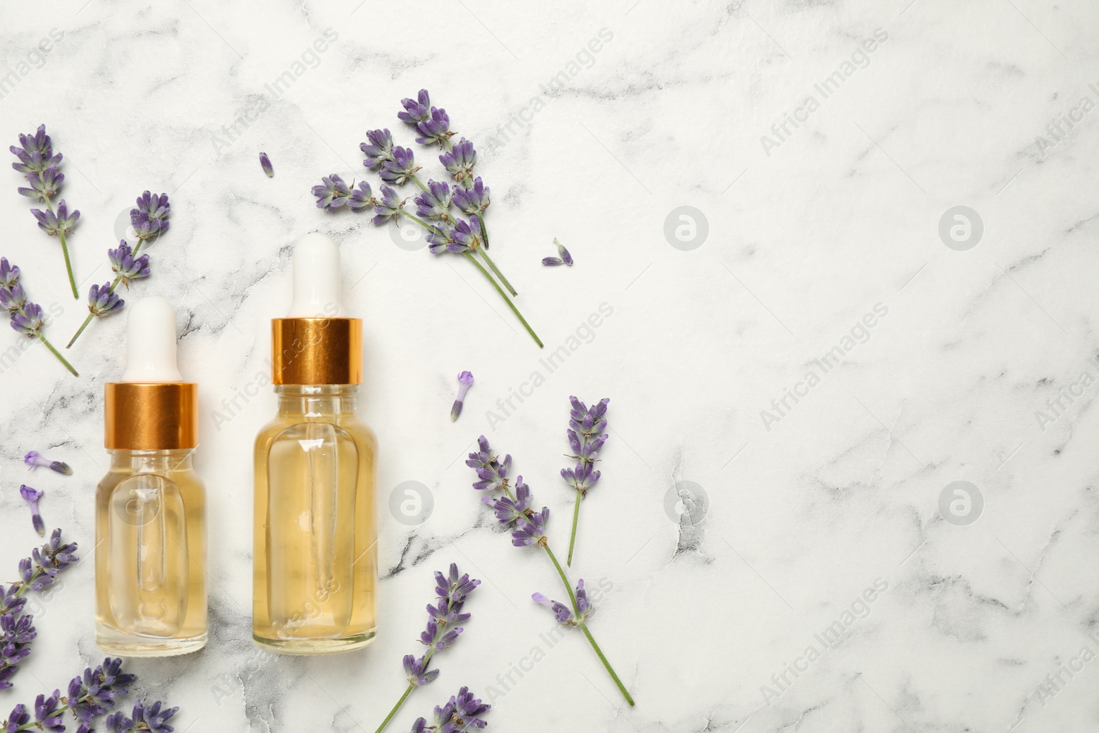 Photo of Flat lay composition with lavender flowers and natural essential oil on white marble table. Space for text