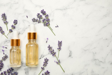 Photo of Flat lay composition with lavender flowers and natural essential oil on white marble table. Space for text