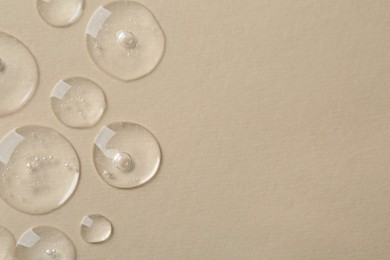 Drops of cosmetic serum on beige background, top view. Space for text