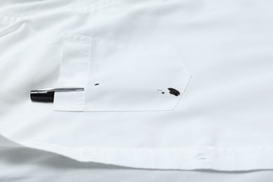 Photo of Pen and stain of black ink on white shirt, closeup