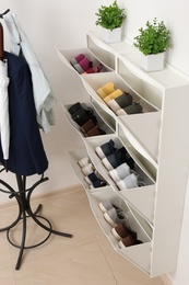 Photo of Shoe cabinet with footwear in room. Storage ideas