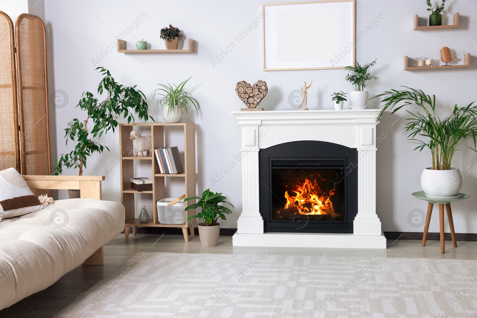 Photo of Stylish living room interior with fireplace, houseplants and beige sofa