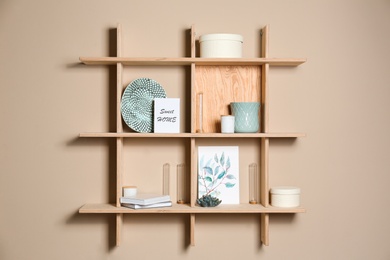 Wooden shelves with different decorative elements on beige wall