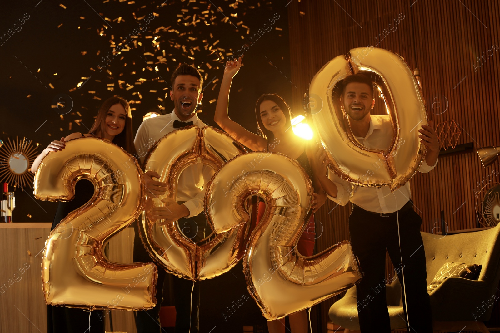 Photo of Young people with golden 2020 balloons celebrating New Year in club