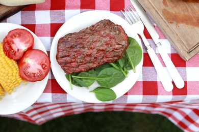 Photo of Delicious grilled steak served on table outdoors, flat lay. Barbecue party