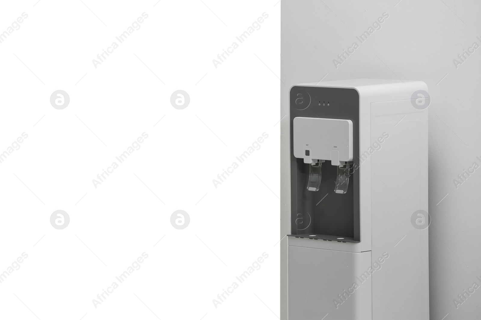 Photo of Modern water cooler near white wall indoors. Space for text